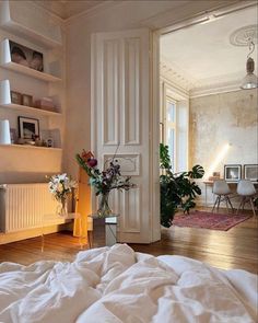 a bedroom with white walls and wooden flooring is pictured in this image, there are flowers on the bed