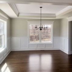 an empty living room with hard wood flooring and white paneling on the walls