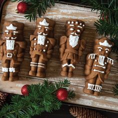 gingerbreads decorated with white icing and decorations on a cutting board next to pine cones