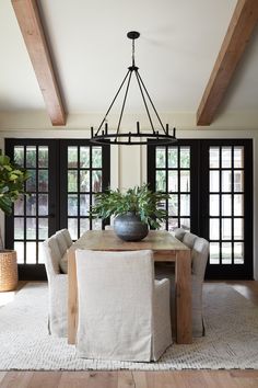 the dining room table is surrounded by two chairs and a vase with a plant in it