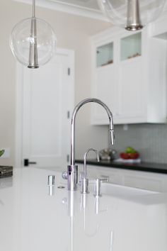 a kitchen with white counter tops and stainless steel faucets hanging from the ceiling