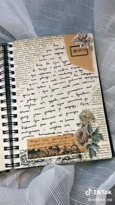 a hand holding a black spiral notebook on top of a white table