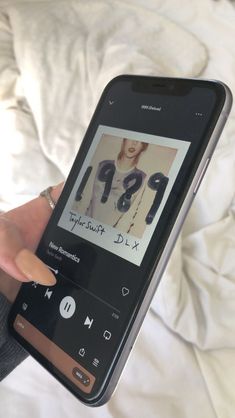 a person holding up a cell phone with an mp3 player on it's screen