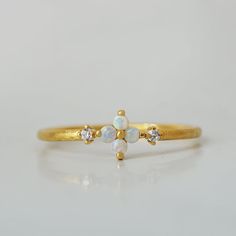 This dainty Forget Me Not ring features four natural Australian opal hugged between two natural diamonds. Set on a polished dainty band. A beautiful ring to wear on your finger to remind you of the beauty of life. Crafted in 14K solid gold in our NYC studio. 14K solid gold Natural Australian opals and diamonds 1.2mm ring band ** This item is specially made for you. Please allow 1-2 week lead time. Shipping:Domestic: Free standard shipping within the U.S.International: Free standard shipping for Dainty Gold Opal Ring In 14k Gold, Dainty Gold Opal Ring In 14k, Delicate 14k Gold Opal Ring, Delicate 14k Gold Opal Ring Gift, Dainty Adjustable Yellow Gold Opal Ring, Opal And Sapphire Ring, Antique Opal Ring, Opal Ring Vintage, Opal Diamond Ring