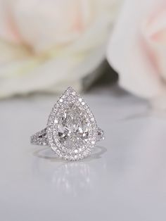 a close up of a diamond ring with flowers in the background