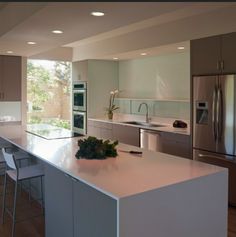 a modern kitchen with stainless steel appliances and white countertops is pictured in this image