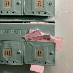 two green mail boxes with pink envelopes sticking out of the top and one is missing