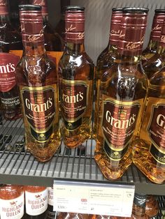 several bottles of liquor are on display in a store shelf with other items behind them