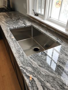 a kitchen counter top with a sink and window in the backgrounf area