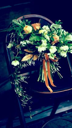 a bouquet of flowers sitting on top of a wooden chair next to a table with an orange ribbon