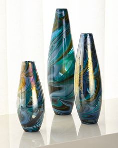 three glass vases sitting on top of a table