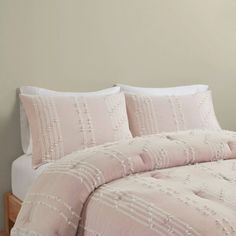 a bed with pink comforter and pillows on it