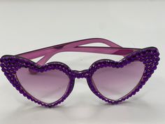 These purple heart shaped sunglasses are bejeweled with purple stones. These are great for Mardi Gras or any day just because you need to sparkle! These could even be a great gift for your favorite Swiftie for her next concert. Purple Sunglasses With Gradient Lenses For Party, Purple Sunglasses With Uv Protection For Party, Party Sunglasses With Purple Gradient Lenses, Party Purple Sunglasses With Gradient Lenses, Purple Party Sunglasses, Purple Heart Sunglasses, Purple Heart-shaped Beaded Jewelry, Cheap Purple Heart-shaped Necklace, Purple Heart-shaped Jewelry With Colorful Beads