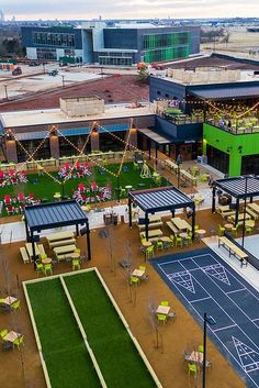 an aerial view of a tennis court and outdoor seating area with lights on the roof