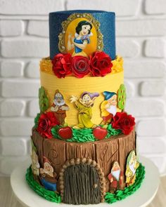 a three tiered cake with snow white and the seven dwarfs on it's side