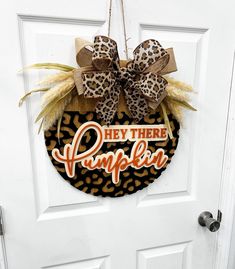 a leopard print door hanger that says hey there pumpkin with a bow on it