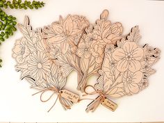 a bunch of flowers with tags tied to them on a table next to some green leaves