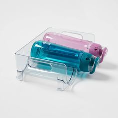 two plastic bottles in a clear holder on a white surface, one is pink and the other is blue