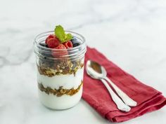 yogurt and granola in a glass jar on a red napkin next to a spoon