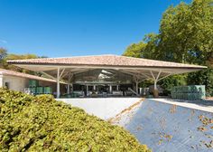 an outdoor pavilion in the middle of a park with lots of trees and bushes around it