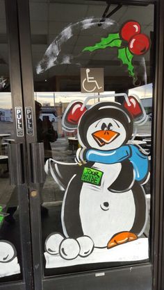 a penguin painted on the side of a glass door with cherries hanging from it