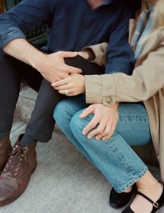 a man and woman sitting next to each other on the ground with their hands together