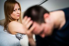 a man and woman sitting on a bed looking at each other's foreheads