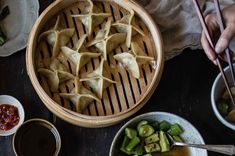 some food is sitting in bowls on a table with chopsticks and dipping sauce