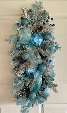 a blue and silver christmas wreath hanging on the front door