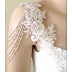 the back of a woman's wedding dress with white flowers and pearls on it