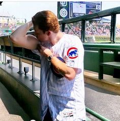 a baseball player leaning on the bleachers at a ballpark with his hands behind his head