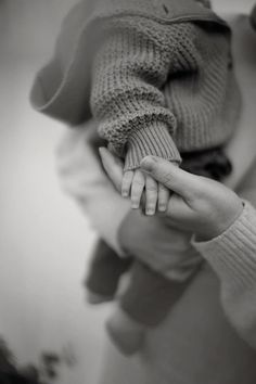 black and white photograph of a woman holding a baby's hand in her lap