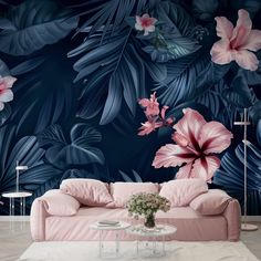 a pink couch sitting in front of a blue wall with large flowers and leaves on it