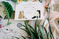 the wedding stationery is laid out with flowers and greenery