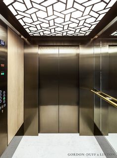 an empty elevator with metal doors and glass panels on the walls, in a public building