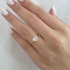 a woman's hand with white manicured nails and a diamond ring