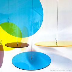 several circular objects hanging from the ceiling in an art gallery, with different colors and shapes