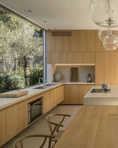 a kitchen with wooden cabinets and white counter tops next to a large window that looks out onto the woods