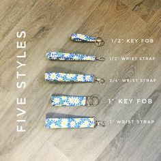 five key fobs with blue and white flowers on them sitting on a wooden floor