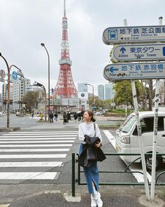 a woman standing next to a street sign in front of the eiffel tower