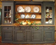 an old china cabinet with plates and pumpkins on it