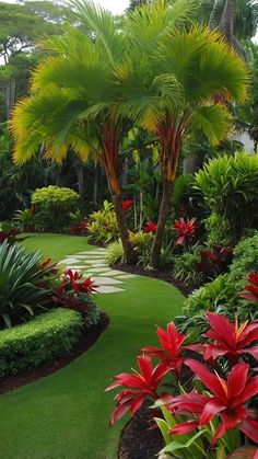 a lush green garden with red flowers and palm trees