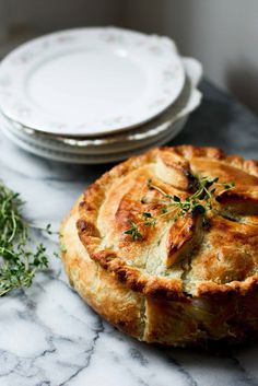 a pie sitting on top of a marble counter next to plates and utensils