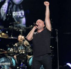 a man standing on top of a stage with his arms up in the air while holding a microphone