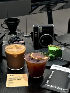 there are two drinks on the table next to a camera and other things around it