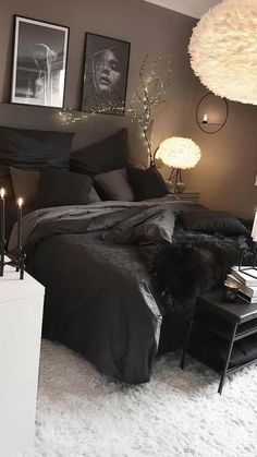 a black and white bedroom with candles on the bed, pictures hanging above the bed