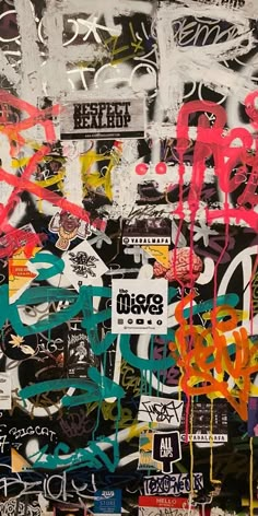 a wall covered in graffiti and stickers with different colors on it's sides