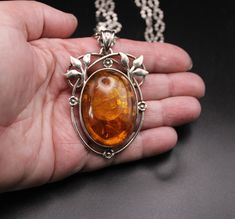 Circa 1980, a stunning amalgamation of elegance and craftsmanship emerges in this Large Solid Silver & Real Baltic Amber Oval Pendant. Set within an open-work floral mount, the radiant Baltic amber exudes warmth and intrigue, capturing the essence of nature's beauty. Crafted with precision and care, the pendant reflects the timeless allure, paired with a Solid Silver Oval Link Crimped Chain by the Italian jeweller Milor, the ensemble embodies timeless elegance and modern charm. Each link is a te Luxury Antique Amber Necklace, Luxury Amber Carved Necklace, Luxury Amber Necklaces With Large Pendant, Luxury Amber Intaglio Jewelry, Luxury Carved Amber Necklaces, Amber Pendant, Amber Bracelet, Dangle Necklaces, Oval Pendant