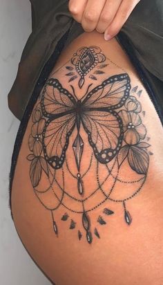 a woman's thigh with an intricate tattoo design on the side and butterfly wings