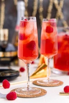 two wine glasses filled with raspberry punch and garnished with fresh raspberries